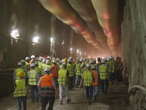 Crew of workers in high-visibility vests gathered inside a construction tunnel