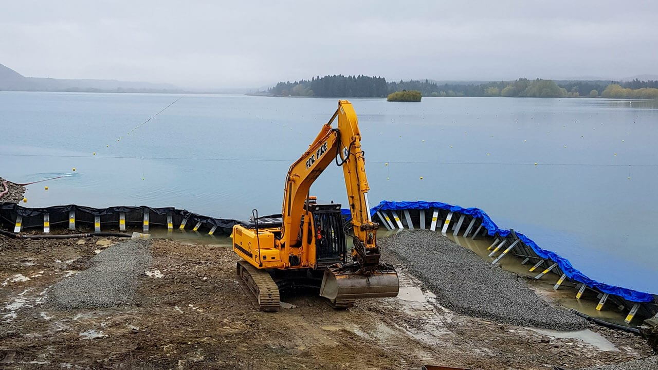 Excavator working from a barge on the water beside a bridge site