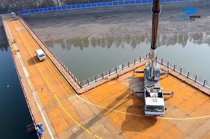 Temporary work platform floating beside a bridge pier