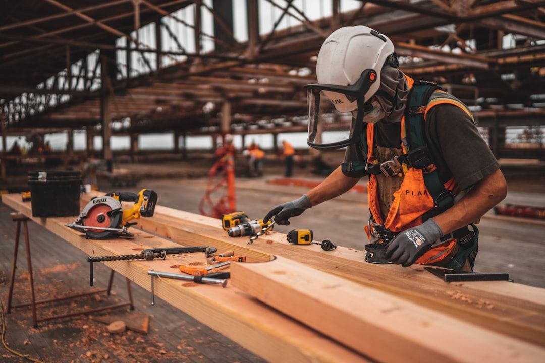 Tradesperson in protective equipment working on timber in a workshop