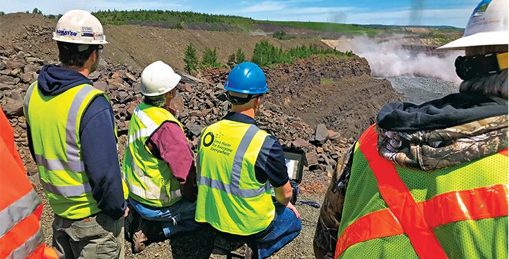 Site crew in high-visibility vests and hard hats observing works across an open excavation