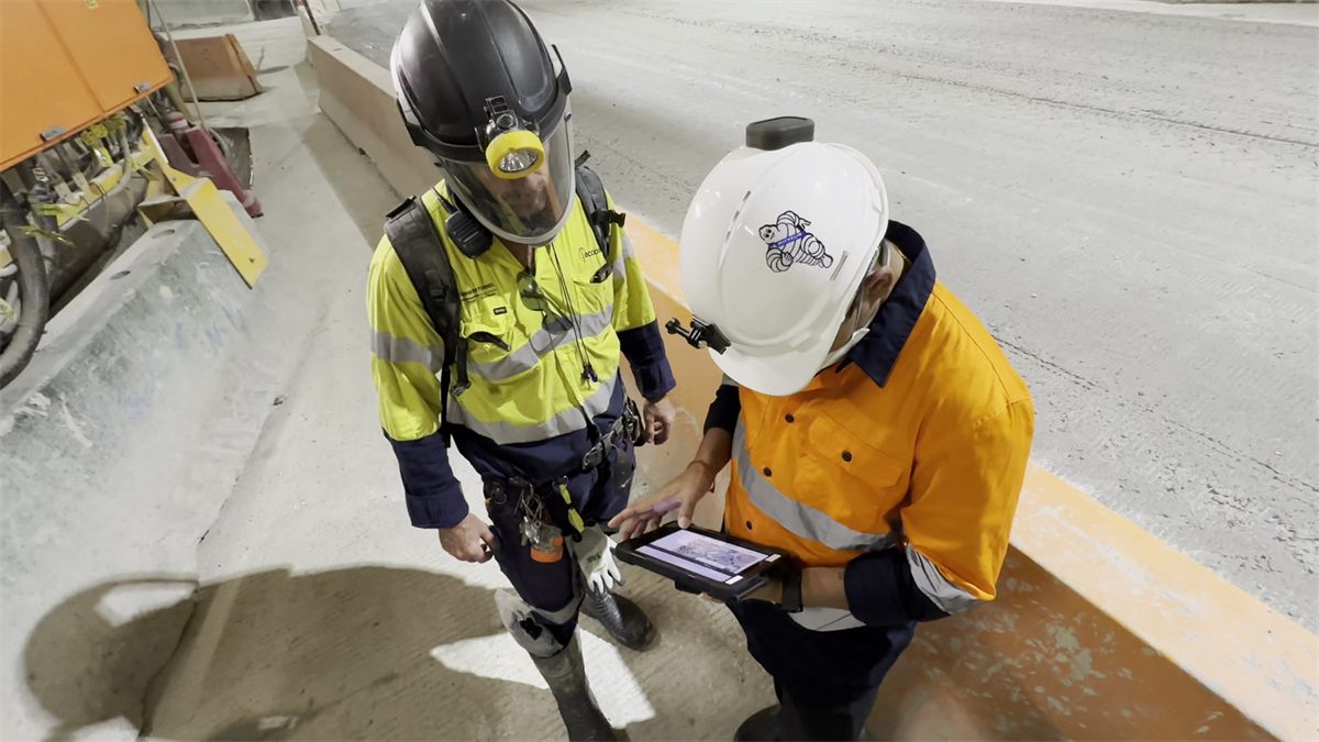 Two workers reviewing site data on a tablet inside a tunnel under construction