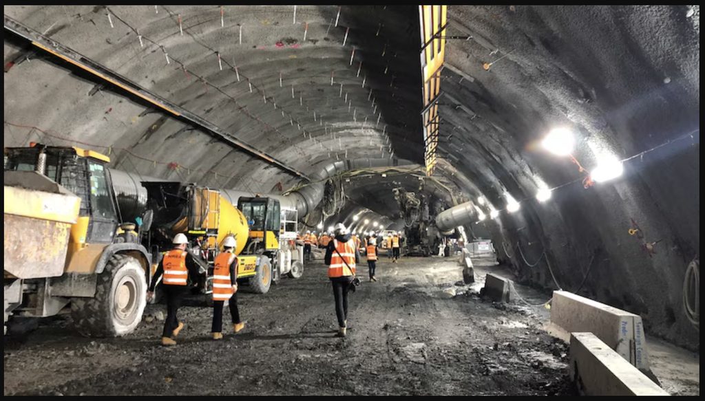 Loader and workers moving through a tunnel under construction