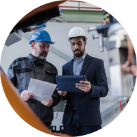 Two stakeholders in hard hats reviewing plans on a tablet