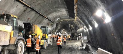 Loader and crew working inside a lit road tunnel