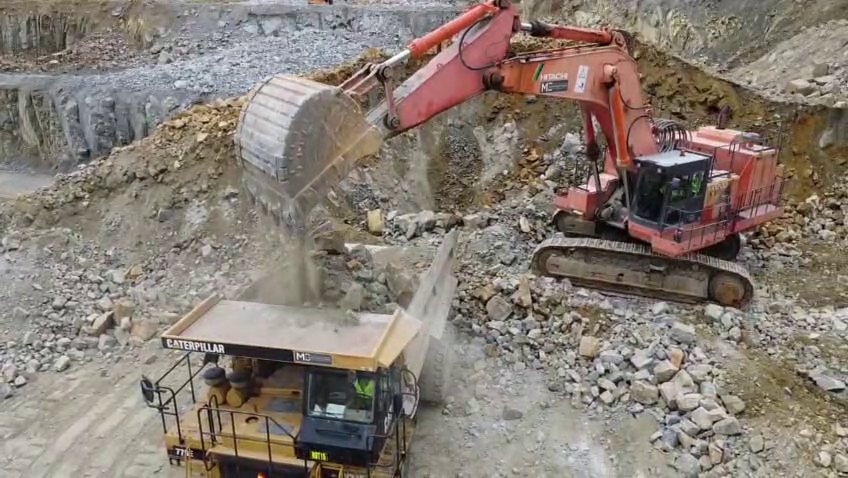 Excavator loading fragmented rock into a haul truck in a quarry